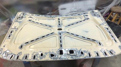 1983 Ford Bronco - Underside of a car hood undergoing repair, showing structural bracing and areas of body filler.