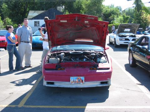 1991 Ford Bronco - Head-on view of a faded red third-generation Pontiac Firebird with its hood raised at an outdoor car meet, exposing a V8 with a round chrom…