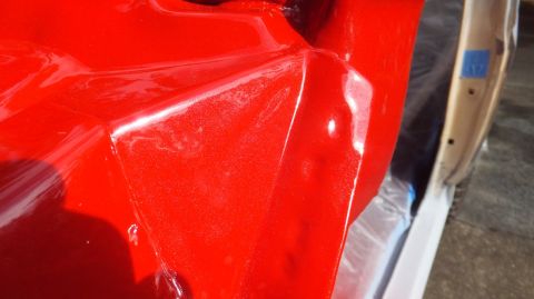 1983 Ford Bronco - Close-up of a red metallic fender and door edge, with blue tape visible on the door jamb.