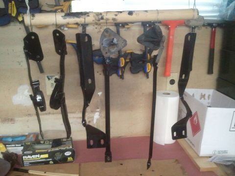 1983 Ford Bronco - Various vehicle pedal assembly components are displayed, some clamped for work, in a garage setting.