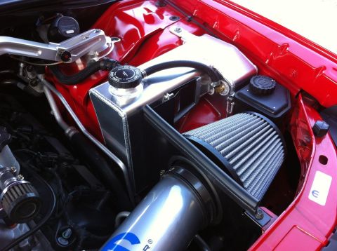 2010 Dodge Challenger - Close-up of a car's engine bay an aftermarket air intake system and a polished aluminum coolant reservoir.