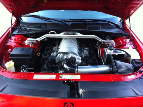 2010 Dodge Challenger - The engine bay of a red Dodge Challenger, showing its V8 engine and performance modifications.