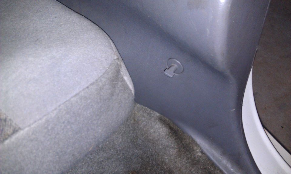 Interior trim panel with a plastic clip visible near a car seat