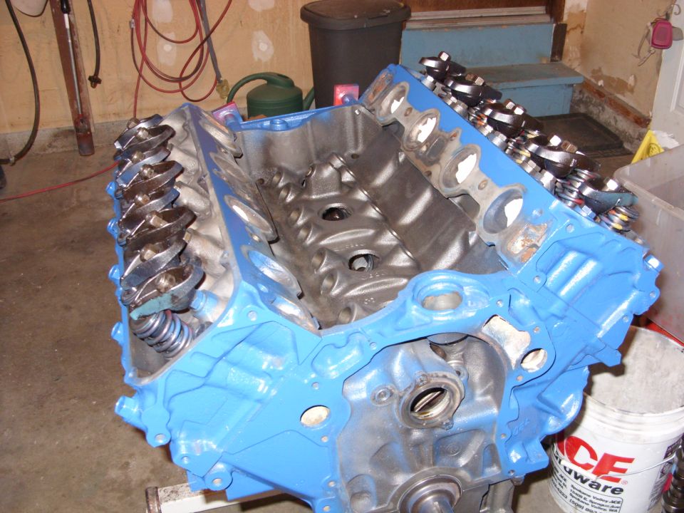 Blue painted engine block with rocker arms and springs visible, angled view