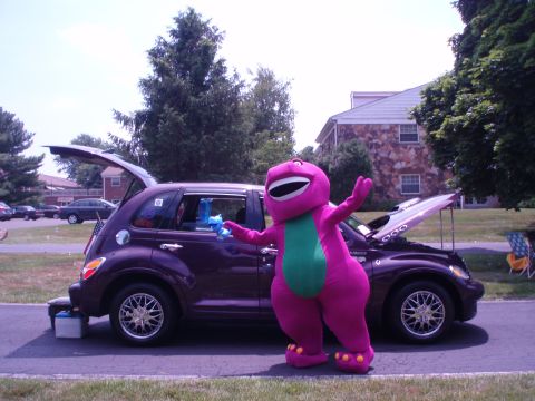 2005 Chrysler PT Cruiser - Barney the Dinosaur mascot poses with a purple 2005 Chrysler PT Cruiser at an outdoor event.