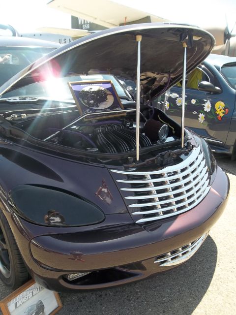 2005 Chrysler PT Cruiser - A custom purple 2005 Chrysler PT Cruiser is displayed with its hood open, revealing the engine bay.