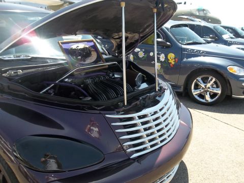 2005 Chrysler PT Cruiser - A custom purple Chrysler PT Cruiser is displayed with its hood open, parked next to another PT Cruiser a Tweety Bird decal.