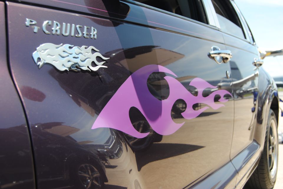 Side view of a purple 2005 Chrysler PT Cruiser with silver eagle and flame decals