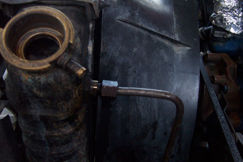Radiator top neck with brass fitting and metal line, next to black fan shroud