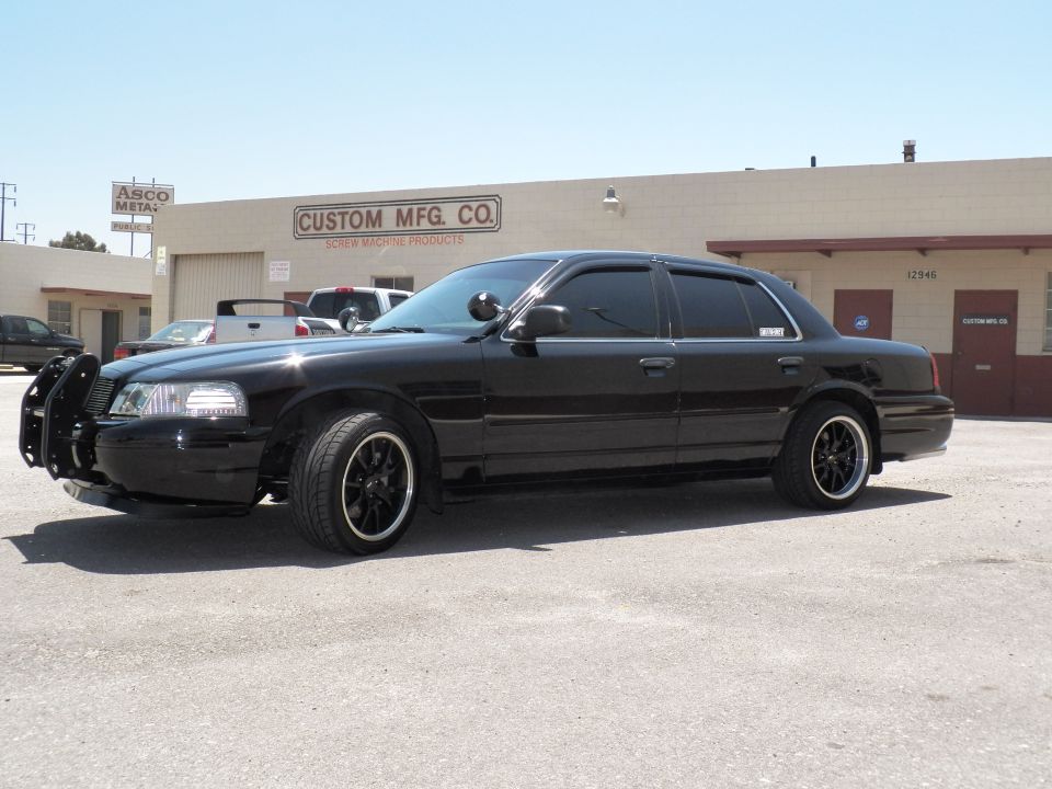 Black Crown Victoria front quarter with push bar and dark machined wheels at Custom Mfg Co warehouse
