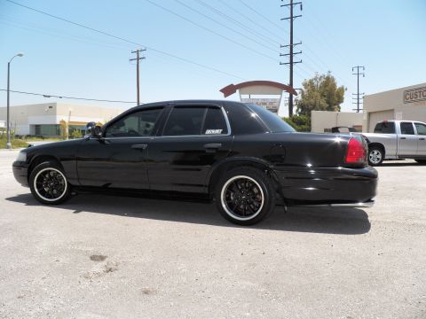 2003 Ford Crown Victoria - Rear-quarter profile of a black Crown Victoria with smoked windows and dark wheels.