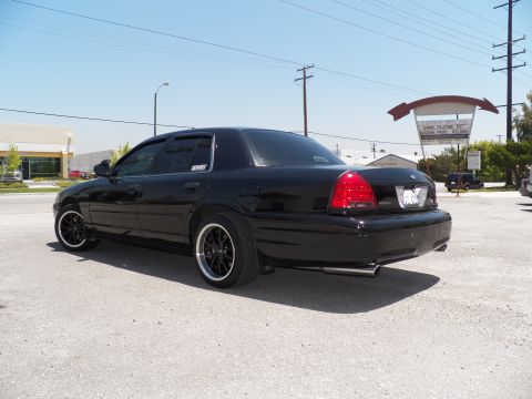 2003 Ford Crown Victoria - Rear-quarter of a black Crown Victoria with dual tips and smoked taillights at an industrial lot.