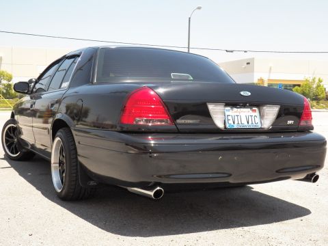 2003 Ford Crown Victoria - Close rear quarter of a black Crown Victoria; California EVIL VIC plate, Crown Victoria and SVT trunk badges visible.