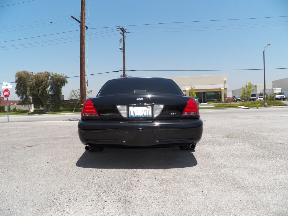 Black Ford Crown Victoria sedan straight-on rear view with dual exhaust in empty lot