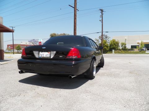 2003 Ford Crown Victoria - Rear three-quarter of a lowered black Crown Victoria; EVIL VIC plate, SVT badge and dual exhaust.