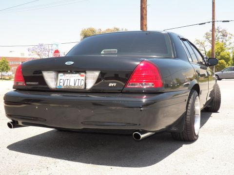 2003 Ford Crown Victoria - Close rear view of black Crown Victoria showing taillights, EVIL VIC plate and dual exhaust tips.