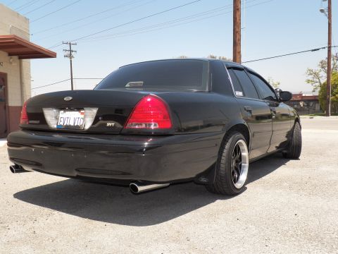 2003 Ford Crown Victoria - Rear right quarter of a lowered black Crown Victoria with EVIL VIC plate and dual exhaust.