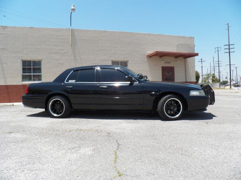 2003 Ford Crown Victoria - Left-side profile of a black Crown Victoria sedan, lowered with black multi-spoke wheels.