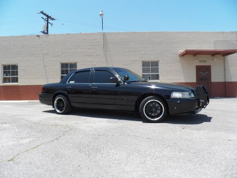 2003 Ford Crown Victoria - Front left three-quarter of a black Crown Victoria fitted with a brush guard and black wheels.
