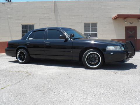 2003 Ford Crown Victoria - Front right three-quarter of a lowered black Crown Victoria with brush guard and tinted windows.