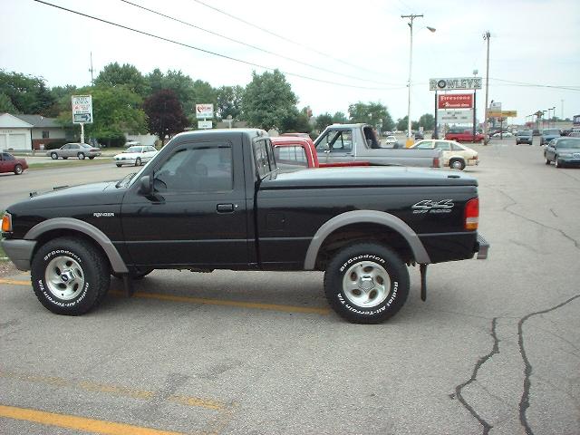 Black Ford Ranger 4x4 pickup with gray lower trim and BFGoodrich tires, side view in a parking lot