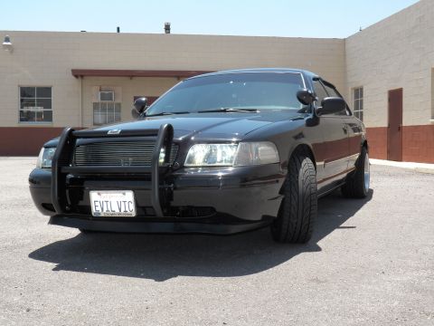 2003 Ford Crown Victoria - Driver-side front quarter of a lowered black Crown Victoria, low stance on dark wheels in a paved lot.