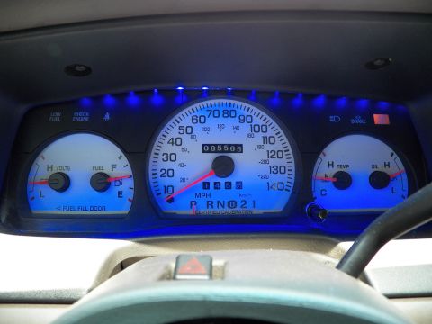 2003 Ford Crown Victoria - Blue-illuminated gauge cluster showing 85,565 miles, PRNDL in Park, MPH speedometer and side gauges.