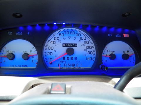 2003 Ford Crown Victoria - Dashboard instrument panel glowing blue, central speedometer flanked by fuel, volts, temp and oil gauges.