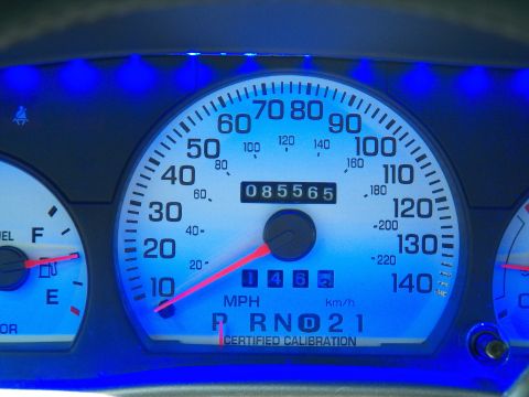 2003 Ford Crown Victoria - Macro of the central speedometer with blue LED ring, trip and main odometer reading 85,565 miles.