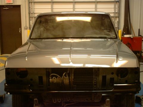 1989 Ford F-150 - The front of a pickup truck is shown in a garage, with the grille and headlights removed for work.
