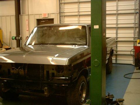 1989 Ford F-150 - A gray pickup truck is parked inside a garage, partially raised on a green car lift.
