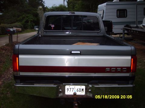 1989 Ford F-150 - Rear view of a gray Ford F-150 pickup truck with a chrome bumper and a red and silver stripe on the tailgate.