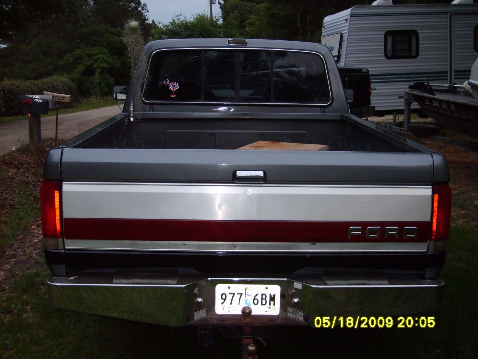 Gray Ford F-150 pickup truck rear view, chrome bumper, red and silver tailgate stripe