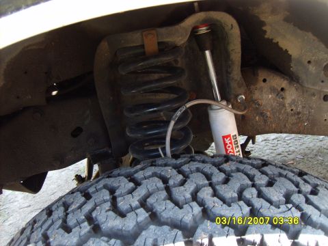 1989 Ford F-150 - This photo shows the suspension system of a truck, including a coil spring and a shock absorber, with a tire visible.