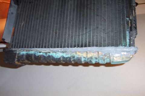 1980 Ford Bronco - A radiator part is shown with sealant and corrosion on its lower tank.