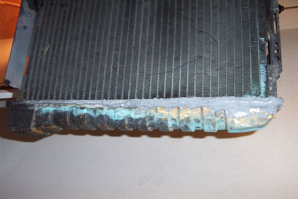 Radiator with gray sealant applied to the bottom tank, showing corrosion