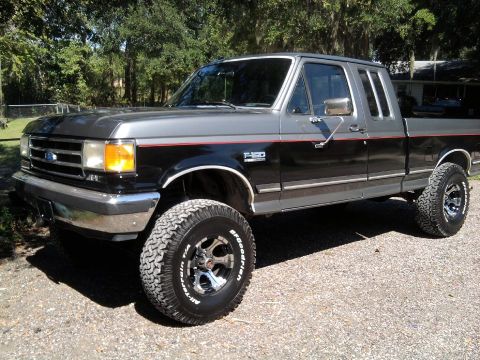 1989 Ford F-150 - This lifted Ford F-150 pickup truck has a two-tone paint scheme with red pinstriping and BFGoodrich All-Terrain T/A tires.