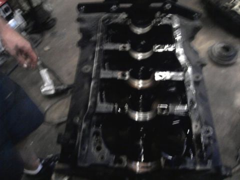 1989 Ford F-150 - Close-up of an engine's crankshaft and block, with a hand holding a tool in the background.