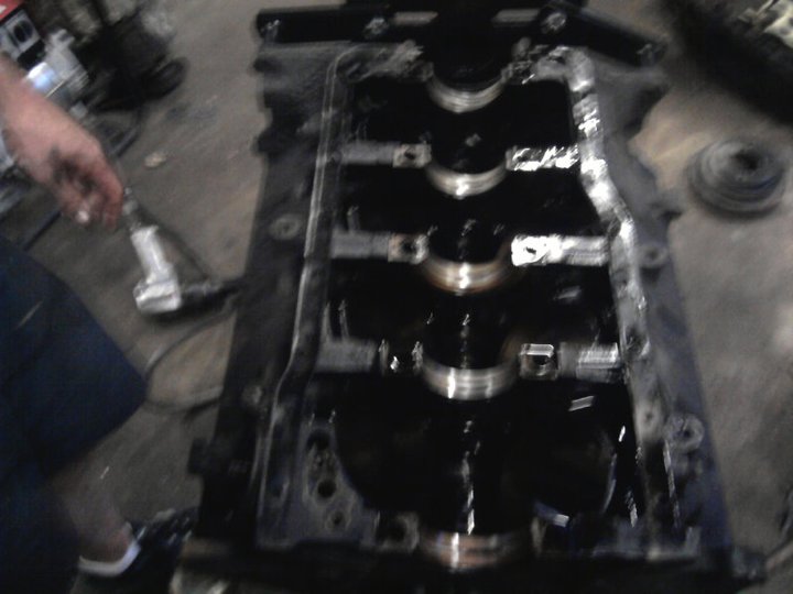 Engine crankshaft and block with oil, a hand holding a tool is visible on the left