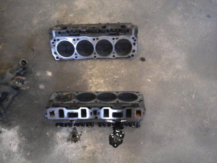 Two engine cylinder heads sitting on a concrete floor
