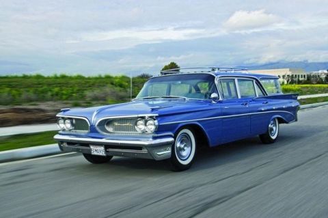1991 Ford LTD Crown Victoria - A classic blue station wagon cruises down the road, its distinctive fins and chrome accents.
