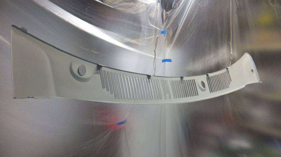 White windshield cowl grille hanging, being painted, with blue tape