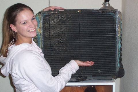 1980 Ford Bronco - A woman presents a used car radiator, likely needing repair or replacement.