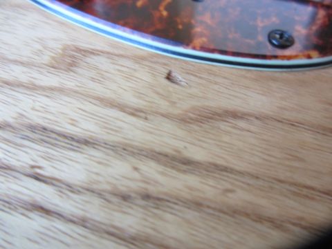 1968 Ford Mustang - A fragment of a musical instrument's body shows wood grain and a tortoiseshell pickguard.