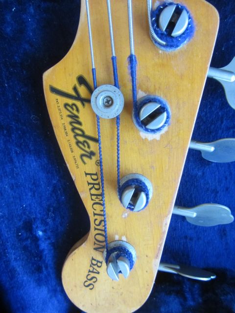 1968 Ford Mustang - The headstock of a Fender Precision Bass guitar shows tuning pegs and strings against a blue background.