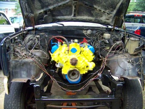 1985 Ford Bronco - Vehicle engine bay during a swap, a bright yellow engine with blue accents.