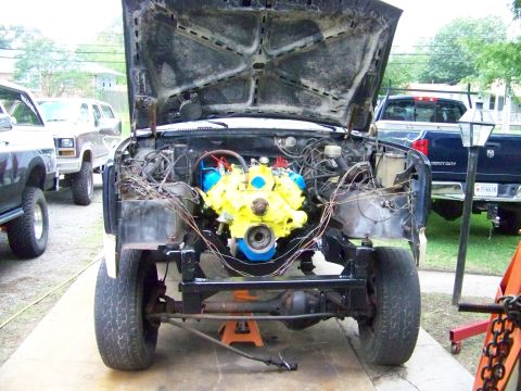 1985 Ford Bronco - The engine bay of a vehicle is shown with the engine removed and placed on an engine stand.