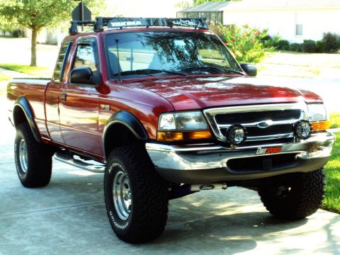 1999 Ford Ranger - Red 1999 Ford Ranger pickup truck parked on a driveway, equipped with a roof rack and auxiliary lights.