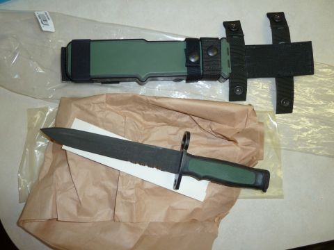 1992 Ford Mustang - A bayonet with a green handle and a black serrated blade lies beside its green and black sheath.