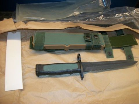 1992 Ford Mustang - A bayonet with a green handle and serrated blade is laid out next to its matching green sheath.